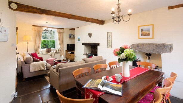Una sala de estar acogedora con un sofá, una mesa de comedor con sillas, una chimenea y una estantería.