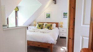 A bedroom with a bed, two bedside tables, a window, and a door. - Drystones (Ambleside)