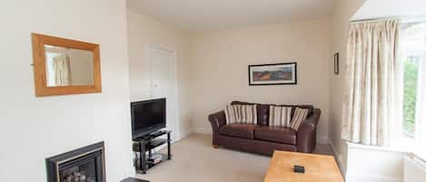 A living room with a fireplace, a television, a sofa, and a table.