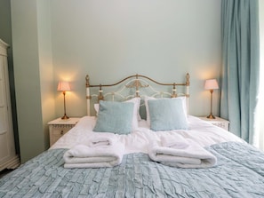 A neatly made bed with pillows, two bedside lamps, and a nightstand with a lamp.
