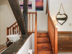 A staircase with wooden railings, a white sink, and a mirror with a heart-shaped frame.