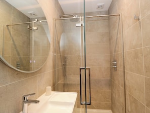 A modern bathroom with a glass-enclosed shower, a white sink, and a large mirror.