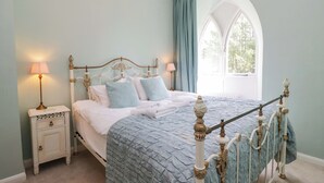 Une chambre à coucher comprenant un lit, des tables de chevet, une fenêtre et un plafond décoratif.