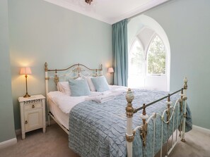 A bedroom with a bed, nightstands, a window, and a decorative ceiling.