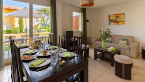Un comedor con una mesa preparada para cuatro personas, un sofá y un televisor.