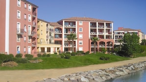 A multi-story hotel with balconies, a swimming pool, and a landscaped garden.