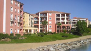 Un hotel de varios pisos con balcones, piscina y un jardín ajardinado.