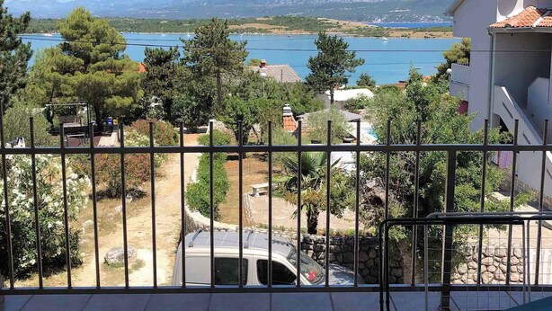 Ein Balkon mit Blick auf einen See, Berge und einen Garten.