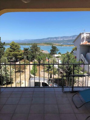 A balcony with a view of a lake, mountains, and a garden. - Holiday apartment with sea view, air conditioning and close to the beach (Klimno)