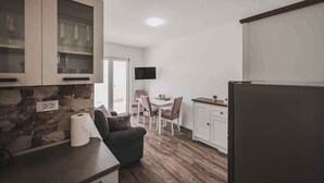 Eine kleine Küche mit Steinrückwand, ein Essbereich mit Fernseher und ein Kühlschrank.
