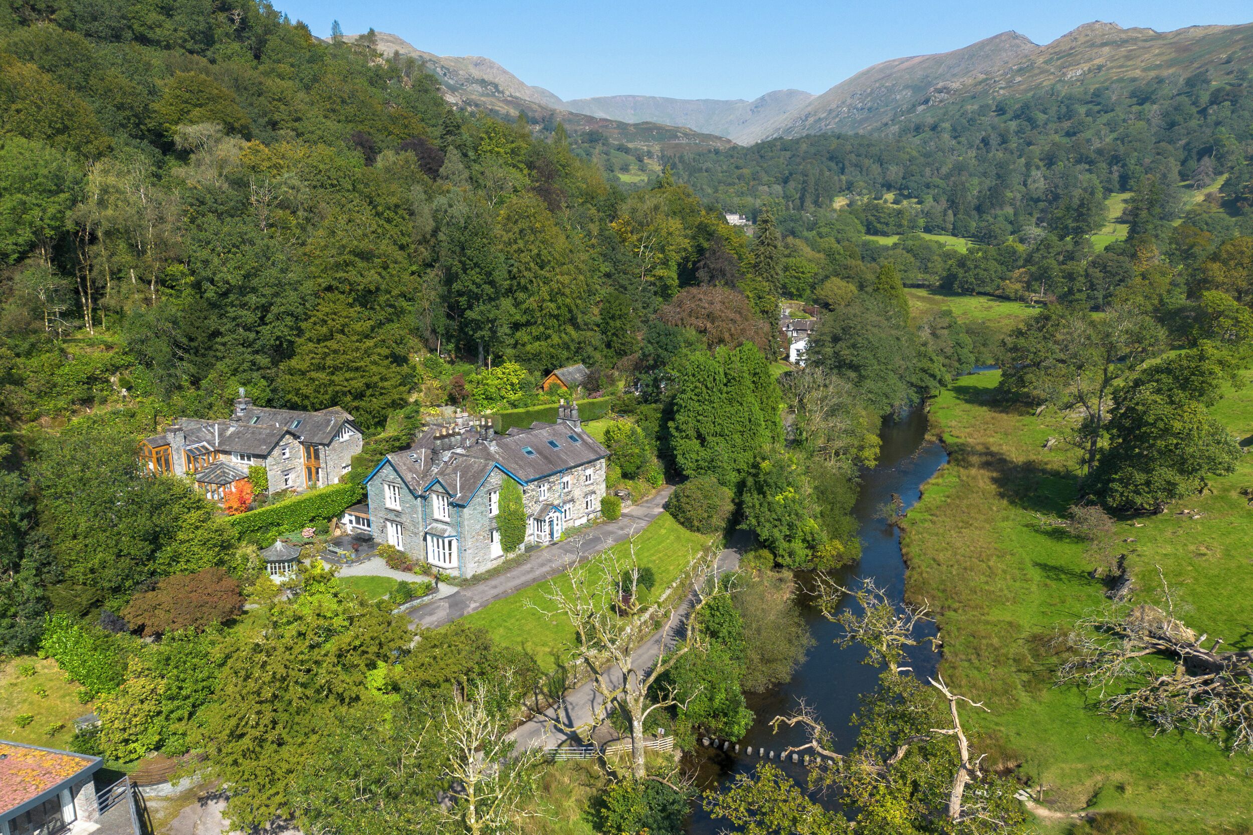 A large estate with multiple buildings, a river, and surrounding greenery.