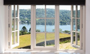A large window with a view of a lake and surrounding greenery. - Hawkrigg Farm (Ambleside)