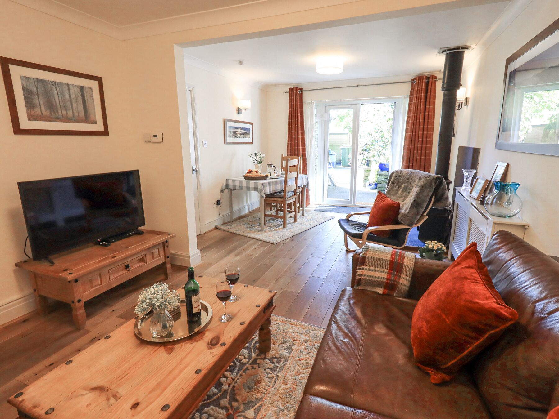 A living room with a television, wooden coffee table, leather sofa, and a dining area with a table and chairs.