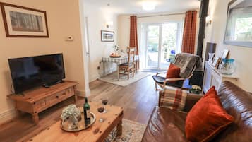A living room with a television, wooden coffee table, leather sofa, and a dining area with a table and chairs.