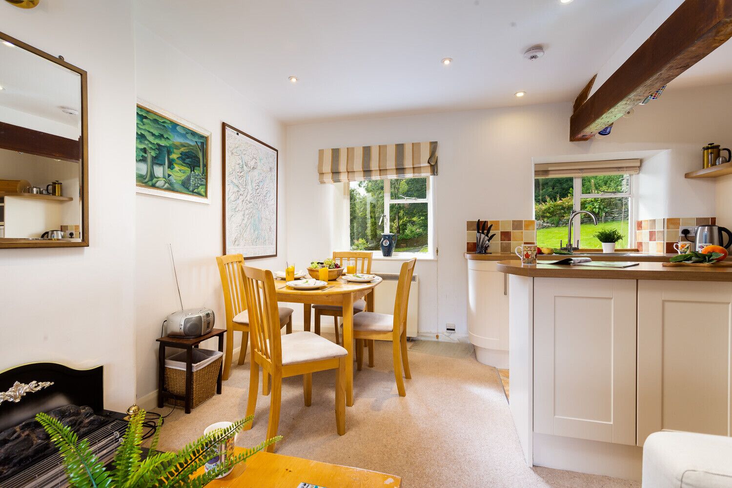 A cozy kitchen with a dining area, featuring a wooden table, chairs, and a window with a view of greenery.