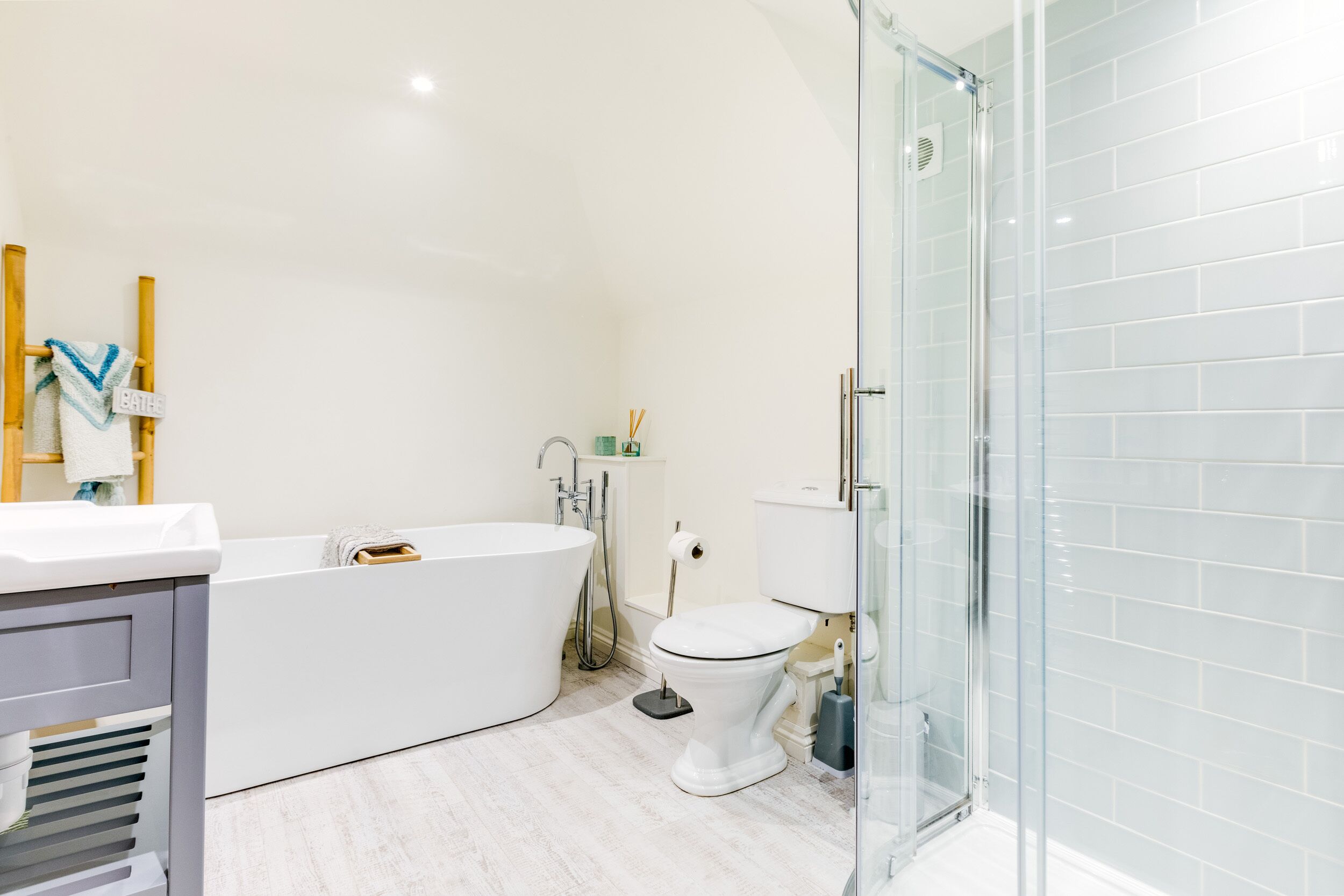 A modern bathroom with a freestanding bathtub, a toilet, and a glass-enclosed shower.