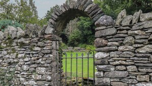 A stone archway leading to a grassy area with a metal gate. - The Rockery Suite (Ambleside)