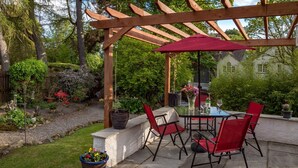 Une terrasse extérieure avec une pergola, des chaises rouges, une table et un parasol rouge.