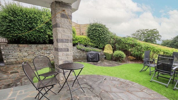 Eine Terrasse mit Steinboden, Metallstühlen und einem kleinen runden Tisch.