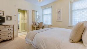 Une chambre à coucher avec un grand lit, une commode, une coiffeuse et un bureau.
