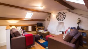 A cozy living room with two sofas, a coffee table, a TV, and a fireplace. - The Cats Bield (Keswick)
