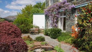 A stone house with a garden, a bench, and a pond. - Betamere (Ambleside)