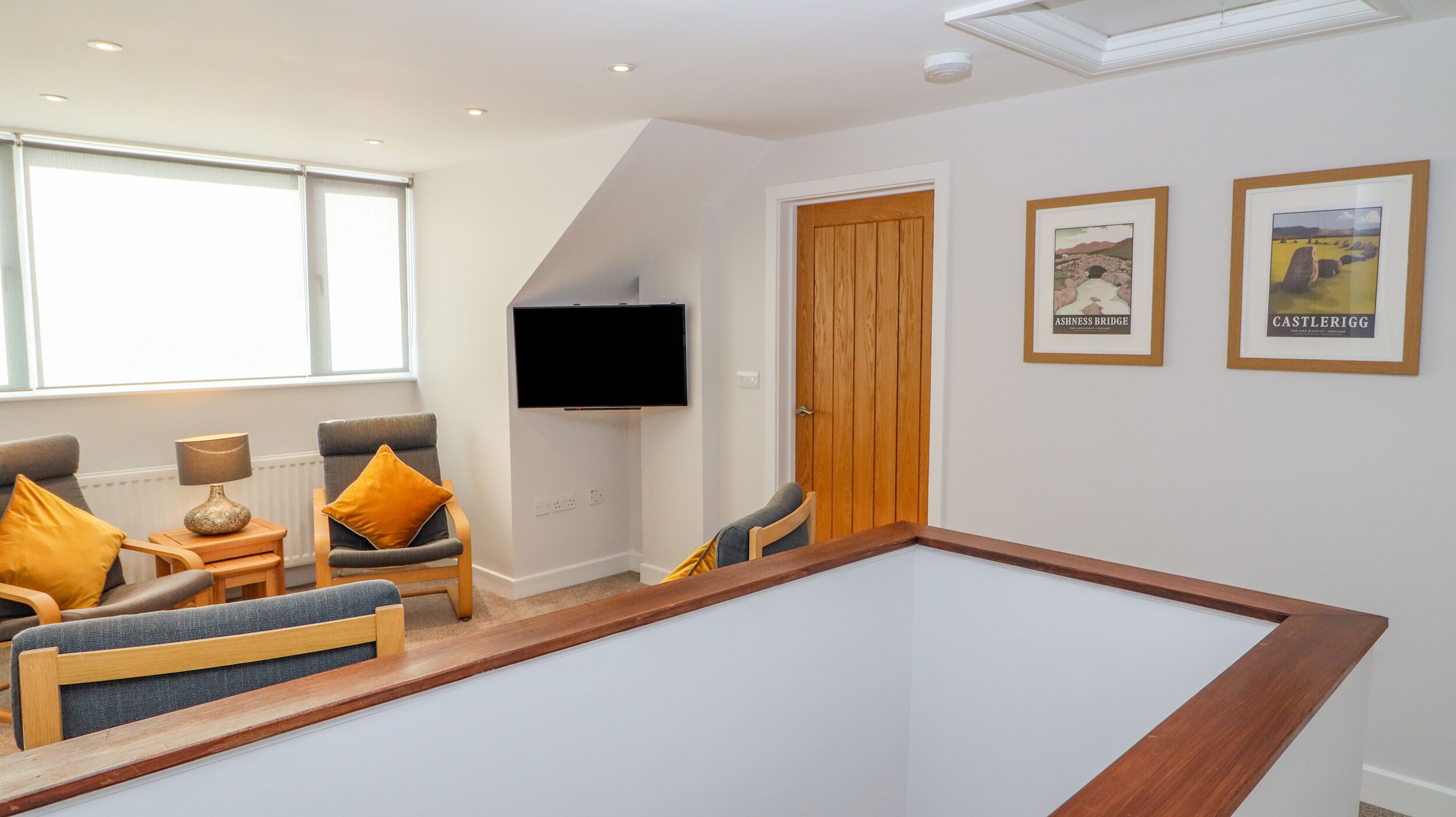 A room with a pool table, a television mounted on the wall, and a door leading to another room.