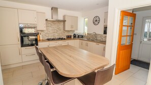 Une cuisine moderne dotée d’un îlot central, de meubles blancs et d’une porte en bois.