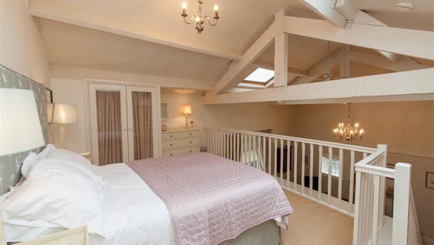 Een slaapkamer met een bed, een kroonluchter, een balkon en een trap.