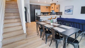 Une cuisine moderne avec des meubles en bois, un îlot central intégré et un coin repas comprenant une table et des chaises.