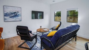Un salon moderne avec un canapé bleu, une table basse en bois et un ventilateur de plafond.