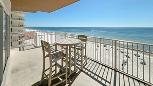 A balcony with a view of the beach, a table, and chairs. - Crystal Shores West 101- Enjoy the View of Paradise (Gulf Shores)