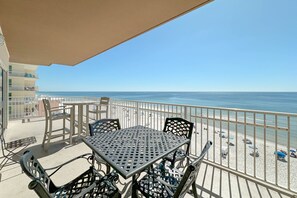 A balcony with a table and chairs overlooking a beach. - Crystal Shores West 101- Enjoy the View of Paradise (Gulf Shores)