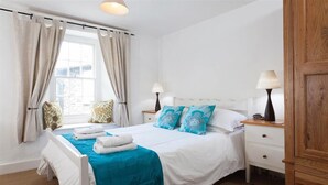 A bedroom with a bed, two bedside tables, a window with curtains, and a wooden wardrobe. - Pollys Cottage (Ambleside)