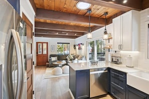 A modern kitchen with a central island, wooden ceiling beams, and a view to the outdoors. - Cobalt by Tahoe Getaways - Luxury 3BR w/ Hot Tub, Walk to Lake - Dog OK (Carnelian Bay)