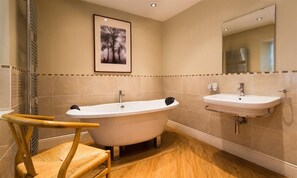 A bathroom with a freestanding bathtub, a sink, and a wooden chair. - Rothay Holme Cottage (Ambleside)