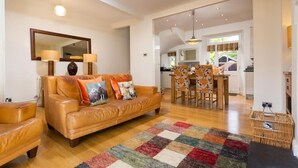 Ein gemütliches Wohnzimmer mit einer Ledersofa, einem farbenfrohen Teppich und einem Essbereich mit Blumenstühlen.