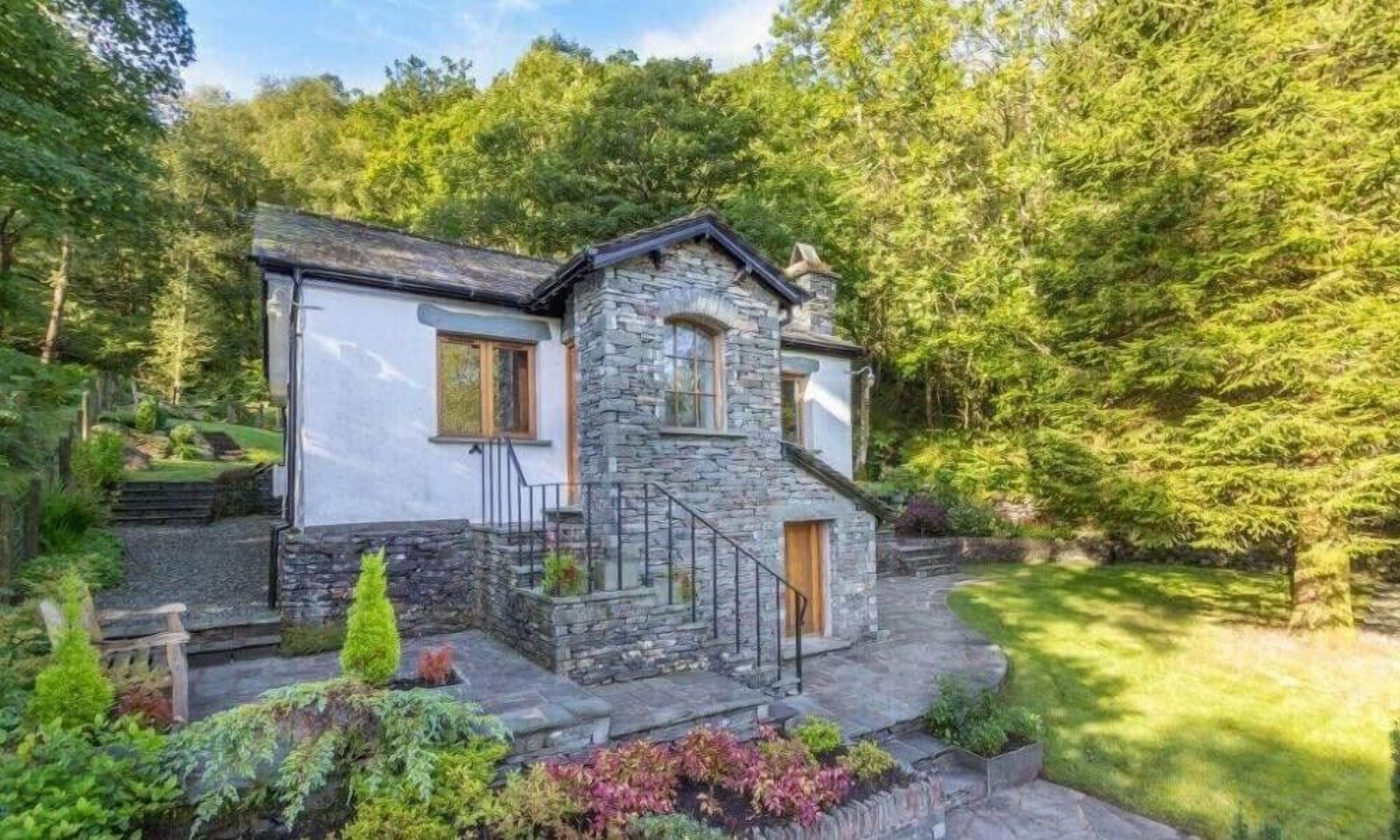 A stone house with a white exterior, a wooden door, and a small porch with steps.