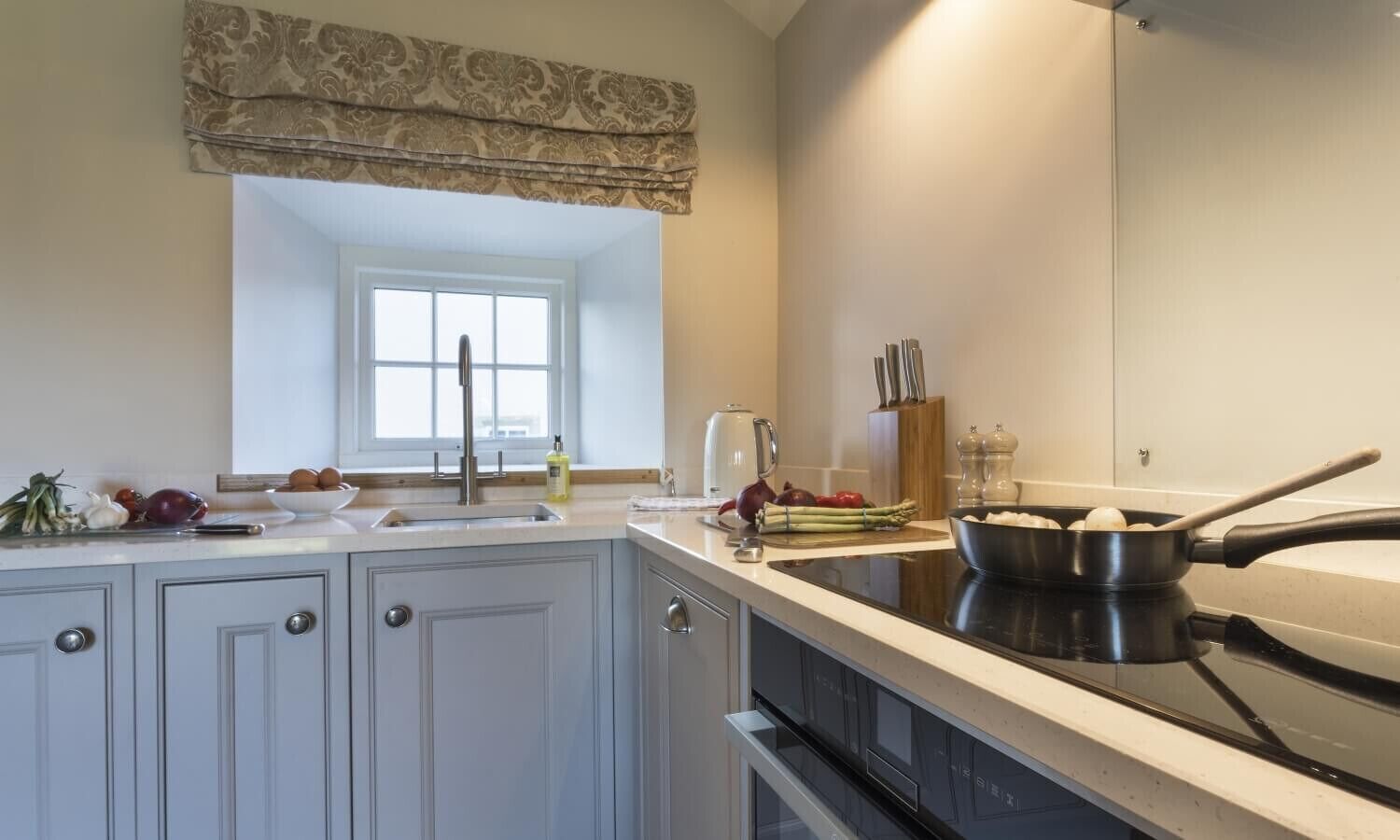 A kitchen with a window, a sink, a stove, and various kitchen items.