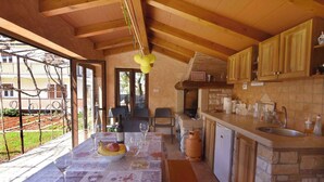 Una cocina con armarios de madera, encimera de piedra y un comedor con mesa lista para dos.