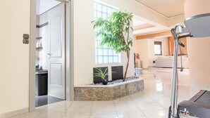 A hotel lobby with a large window, a potted plant, a treadmill, and a reception area. - Villa Archodia - With Private Pool (Prines)