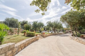 A paved driveway leading to a building with stone walls and potted plants.