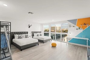 Ett modernt hotellrum med två sängar, en balkong med utsikt över staden och en trappa med ett geometriskt mönster.