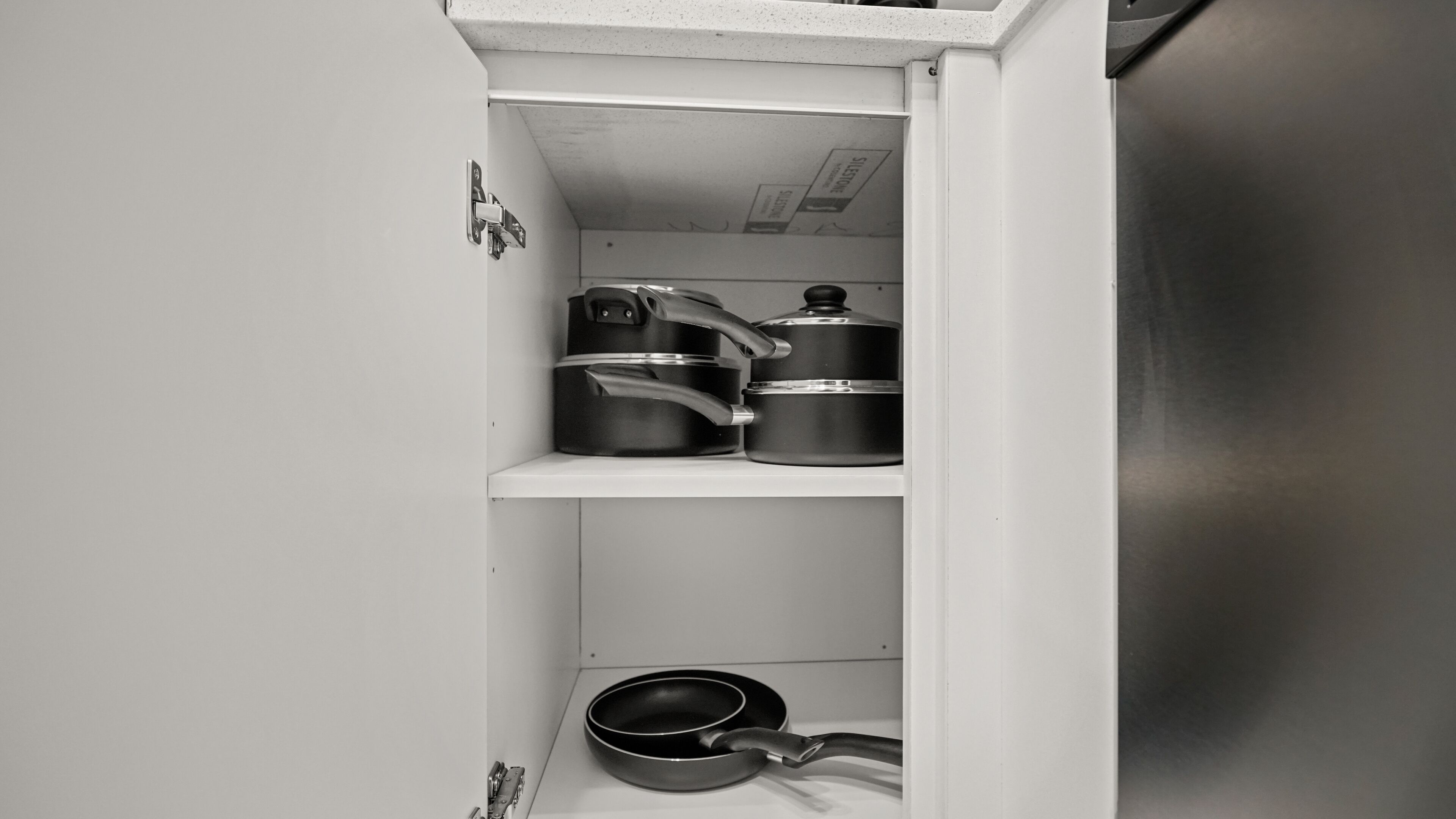 A kitchen with stainless steel appliances, including a refrigerator, a stove, and a pan.