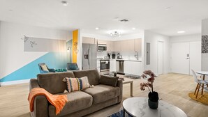 En moderne stue med sofa, sofabord og et lille spiseområde.