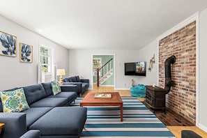A modern living room with a sofa, coffee table, and a brick fireplace.