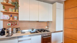 Une cuisine moderne avec des meubles blancs, une cuisinière en acier inoxydable et un plan de travail en bois.