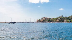 Un port de plaisance avec des bateaux amarrés, un ciel dégagé et des bâtiments situés sur une colline.