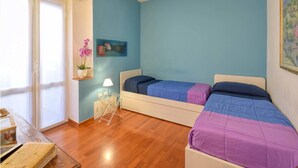 Une chambre avec deux lits, une petite table, une lampe et un tableau au mur.