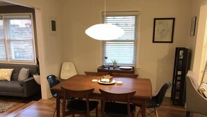 A dining area with a wooden table and chairs, a hanging light fixture, a sofa with cushions, and a window with blinds. - 7 Miles to Masters Tournament - Less Traffic - Sleeps 8 (North Augusta)